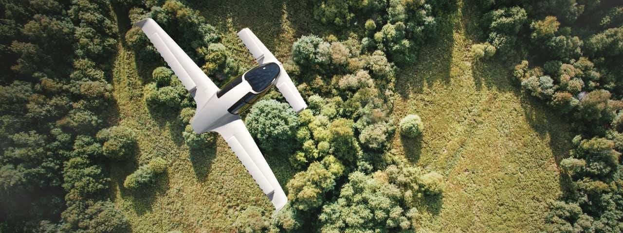 A Lilium Jet flying over a wooded countryside on a sunny day