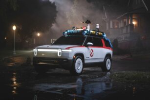 White Rivian Ecto-R1 parked at night with Ghostbusters graphics and roof-mounted equipment